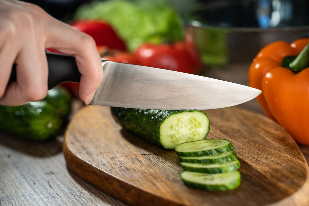 胡椒男手拿刀在木板上切黄瓜的画面准备蔬菜特写