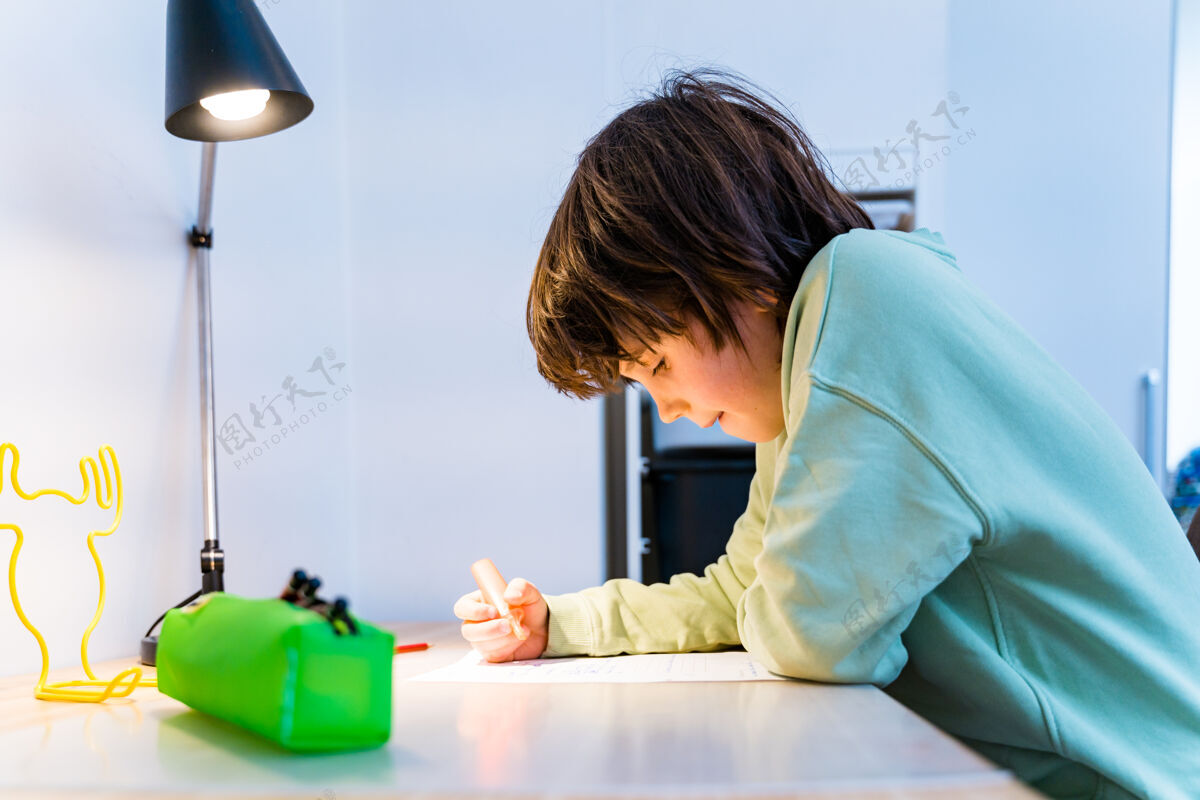 可爱小男孩坐在桌子旁做作业家集中儿童写作家庭教育概念学习知识聪明