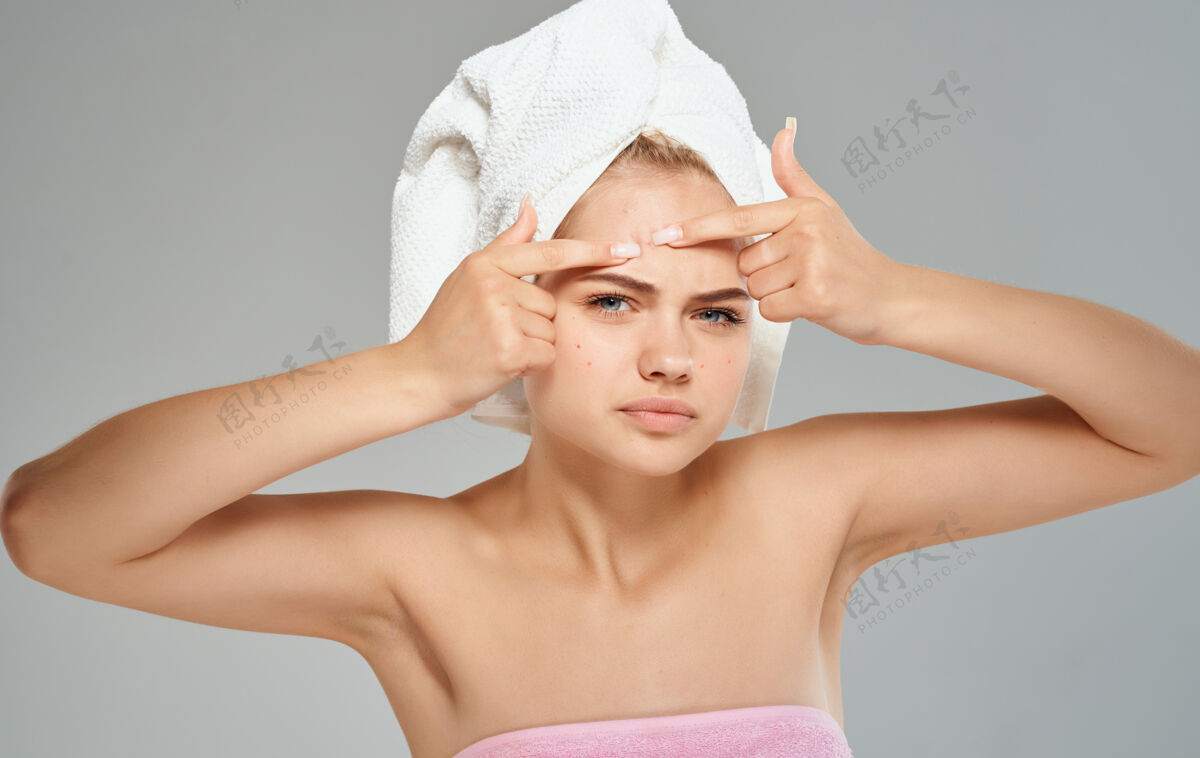 皮肤情绪激动的女人挤出她额头上的青春痘和头上的毛巾裸露的肩膀裁剪视图女人头手指