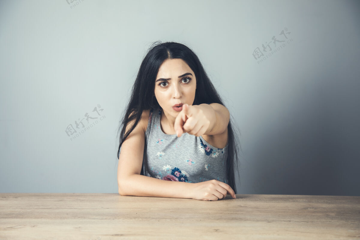 表演愤怒的女人手指你在桌子上签名女人脸警觉