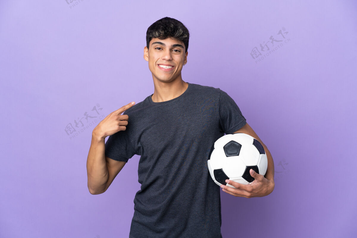 男子一个年轻的足球运动员在孤立的紫色背景下竖起大拇指运动比赛表情