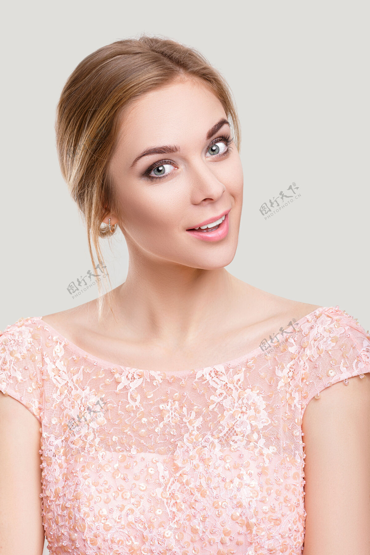 华丽年轻漂亮的金发性感女人的肖像 在灰色背景上穿着粉色鸡尾酒裙年轻脸粉色