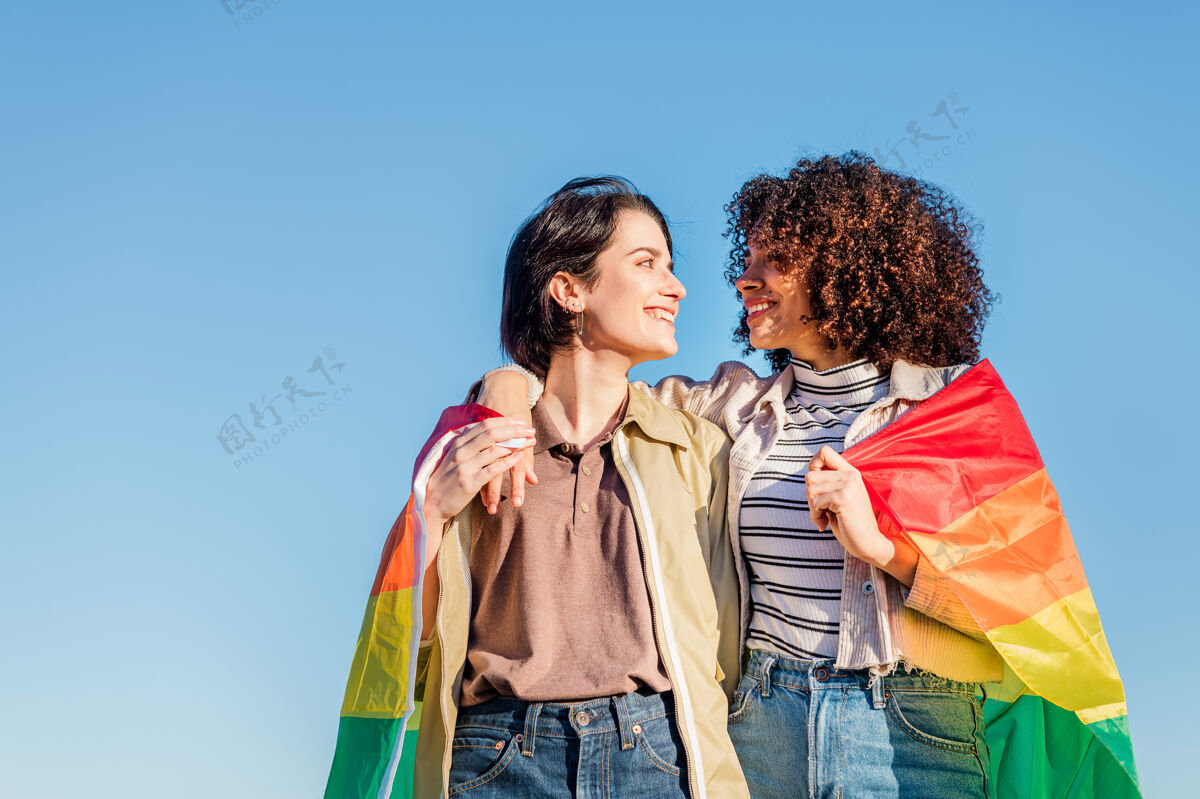 女同性恋一对戴着彩虹旗的可爱女人平等非洲拥抱