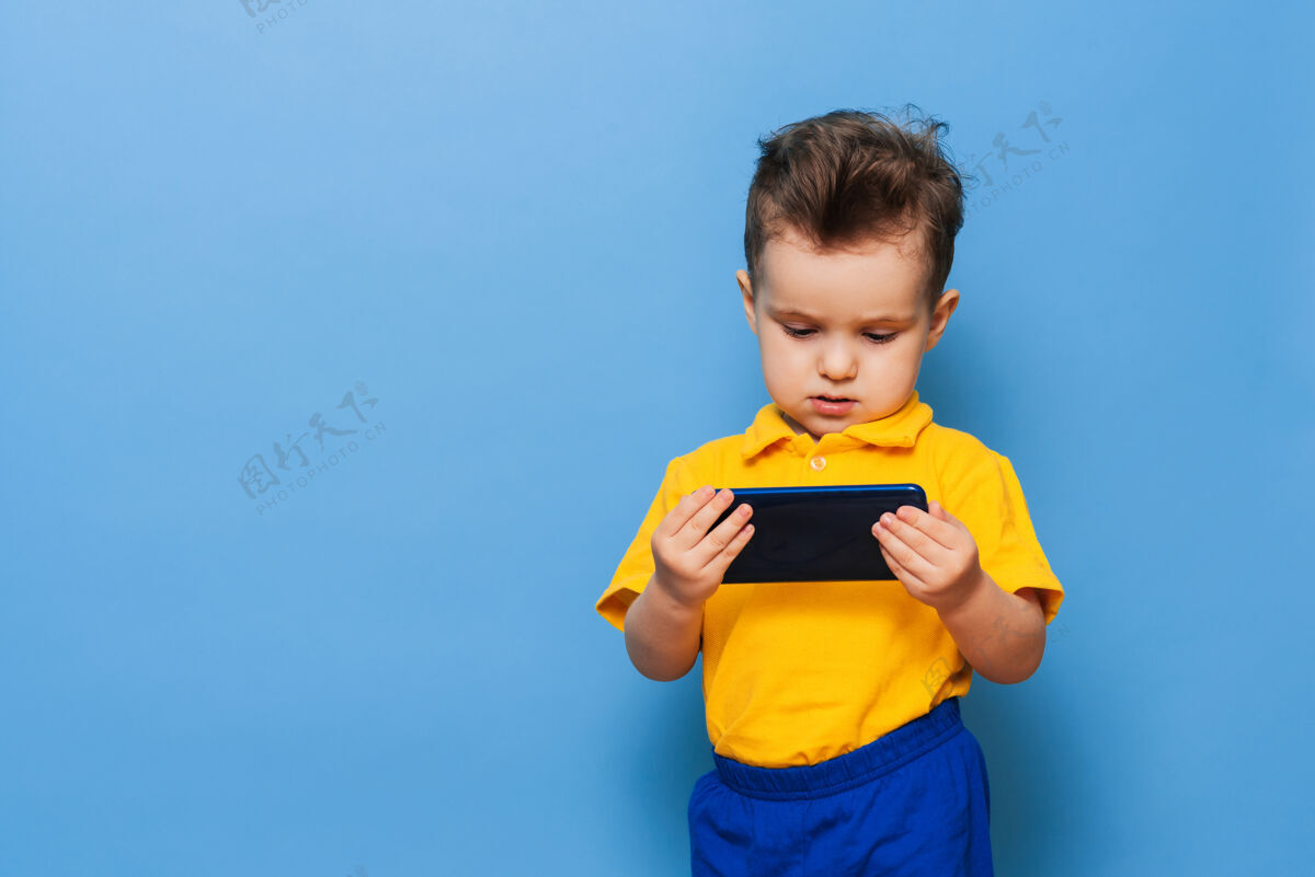 人一个小男孩看着手机屏幕孩子手机电话