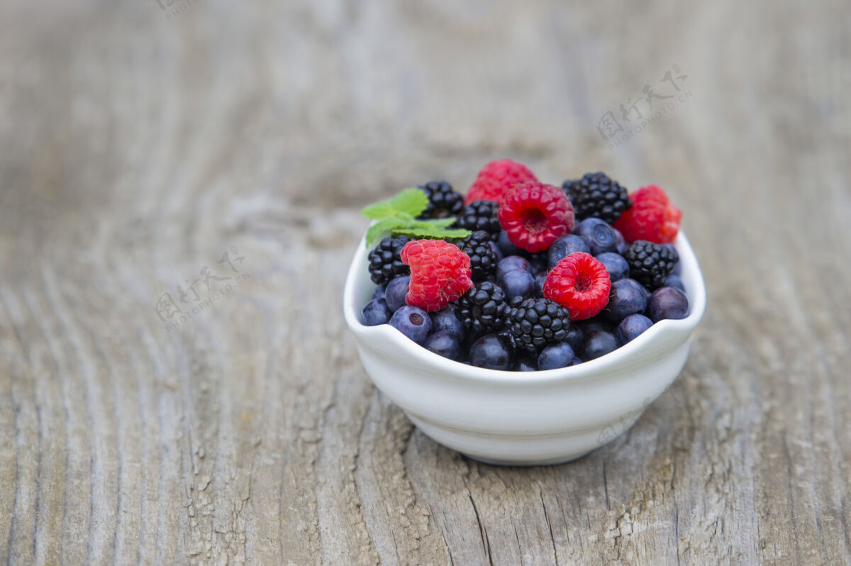 有机把蓝莓 黑莓 覆盆子放在旧木桌背景上的木碗里水果美味健康
