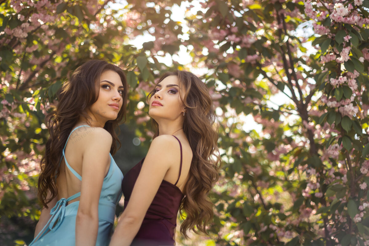 花开时尚双胞胎模特的画像 完美的化妆和发型站在樱花附近童话花开花园