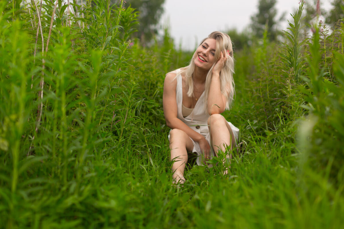 草一个穿着白色夏装的金发女孩坐在高高的草地上户外衣服女性