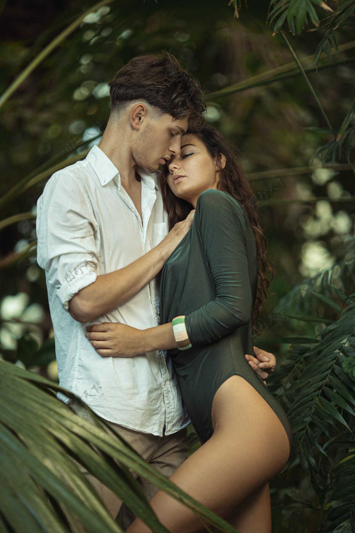 年轻一对浪漫的情侣在热带丛林中的异国植物中棕榈花园一起