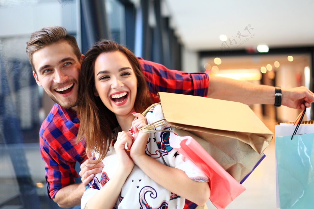 男人销售 消费主义和人的概念-幸福的年轻夫妇购物袋走在商场漂亮买家室内