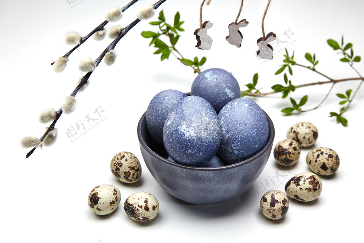 大理石一只碗里有彩绘的鸡和鹌鹑蛋 还有带木制玩具兔子的阴阳柳枝复活节彩蛋传统壳