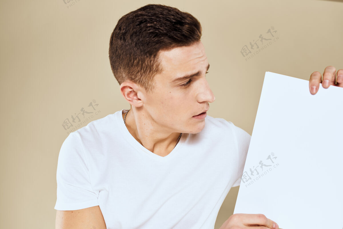 男性穿白色t恤的人手里拿着一张纸复印空间裁剪成米黄色公司信息沟通