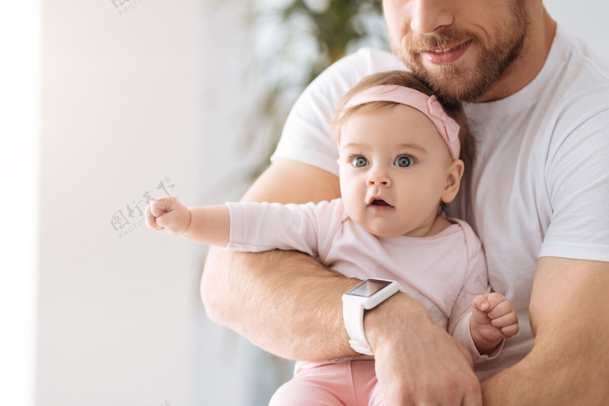 世代有趣的世界我很惊讶小女婴躺在父亲的手里 一边看一边表示兴趣爱童年父母