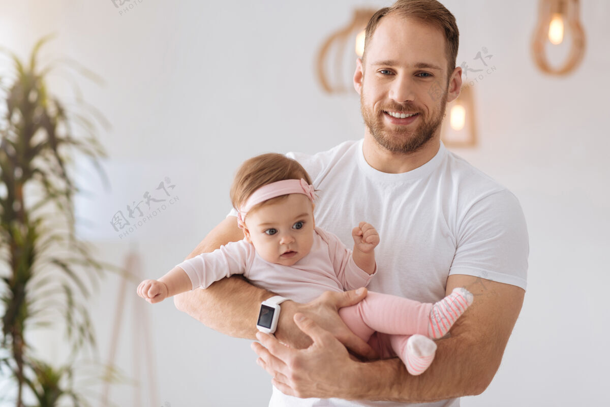 腰杆向上快乐的父亲时代体育坚强快乐的父亲站在家里 抱着新生儿 同时表达积极的情绪高兴爱放松