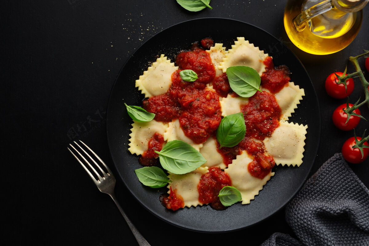 方形美味的意大利馄饨配番茄酱和罗勒 放在深色盘子里馄饨酱汁罗勒