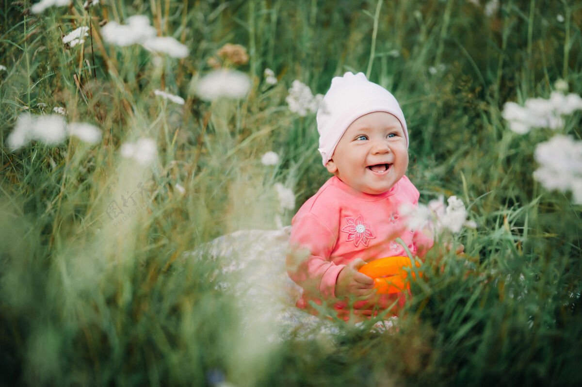 花园美丽快乐的小女孩坐在公园里开着白花的绿色草地上玩耍草地光明