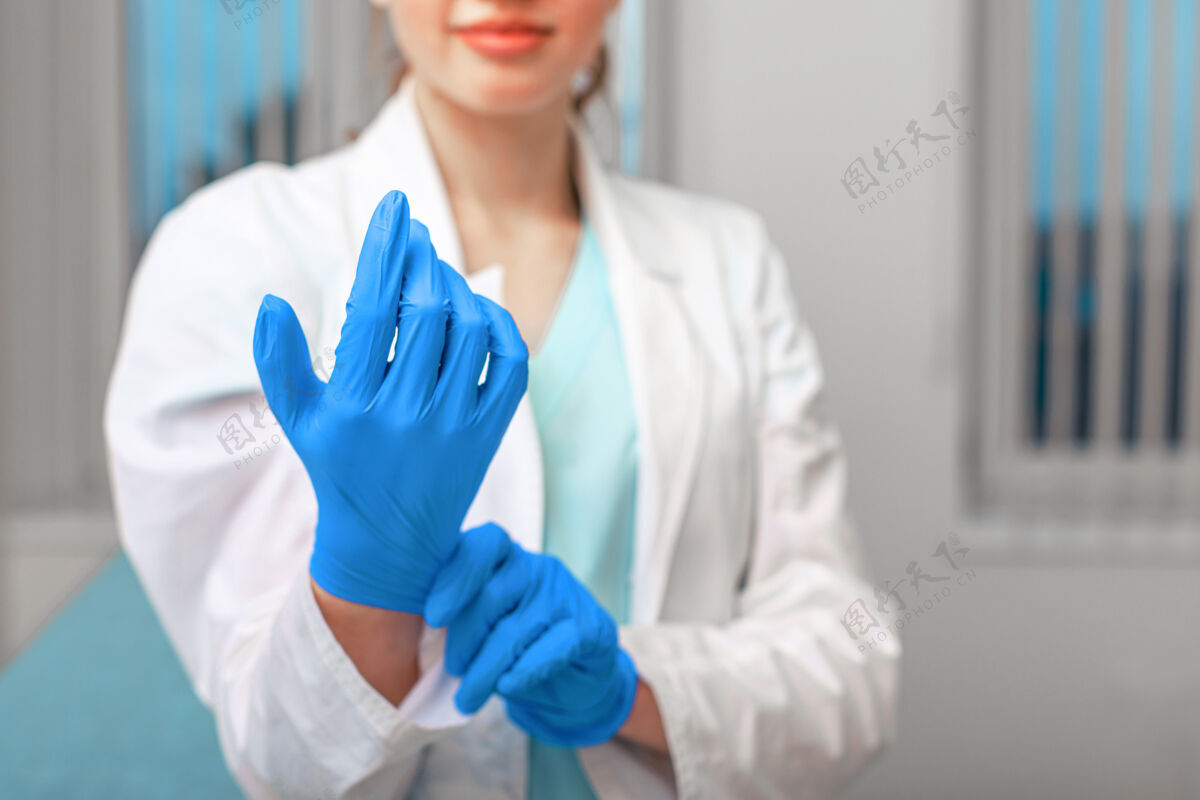 防护医生的手戴上乳胶手套在医院里 一个女人穿着医生的工作服 戴着乳胶手套防止病毒和细菌危害健康工作医生专业