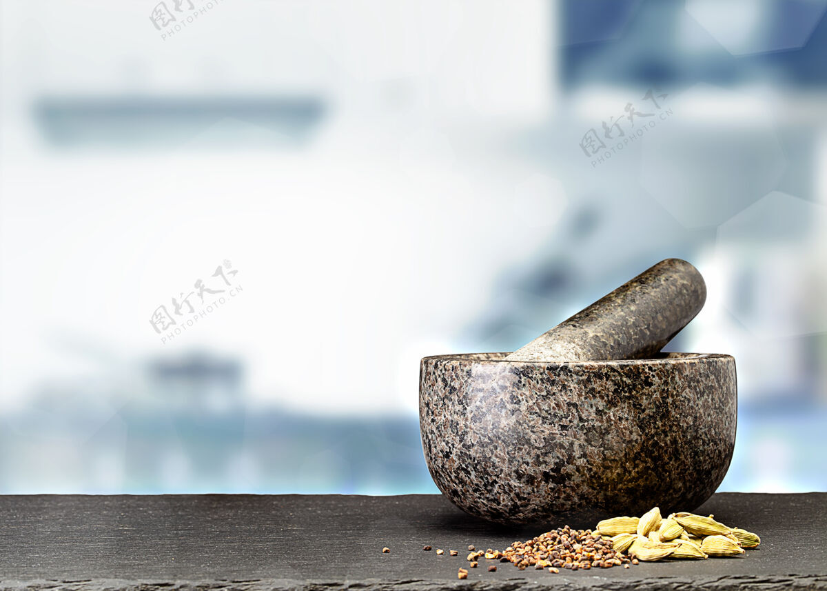 花岗岩在模糊的厨房前面的桌子上放着花岗岩砂浆和香料研磨研磨机砂浆