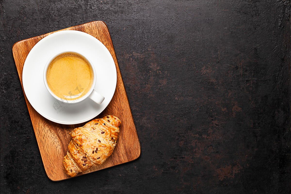 新鲜一杯咖啡和羊角面包放在木板上放在古老的乡村背景上食物顶部木板