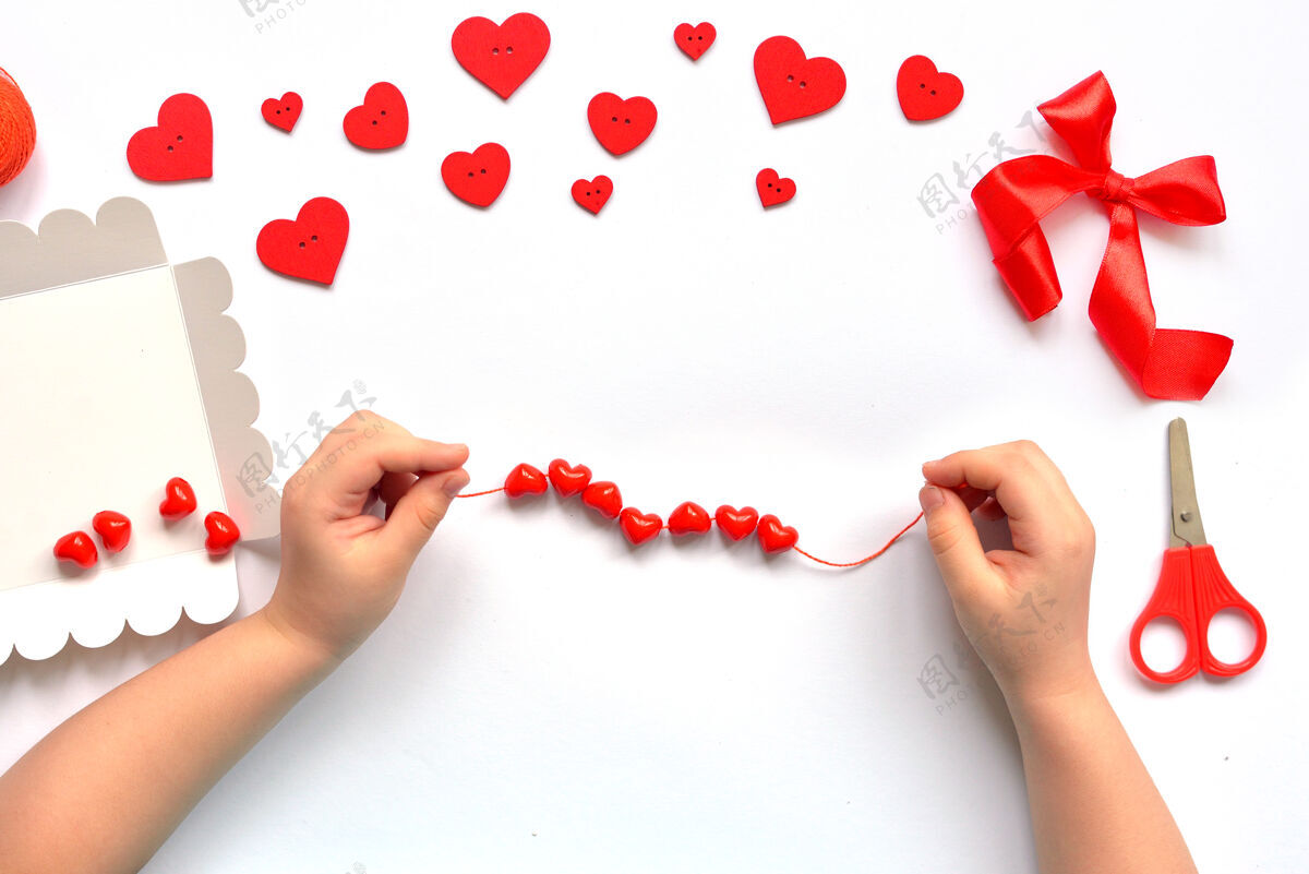 手指Diy的孩子们在情人节的时候把红色的珠子串在心形的绳子上手镯手工制作宝贝装饰.工艺品概念情人节步骤绿松石