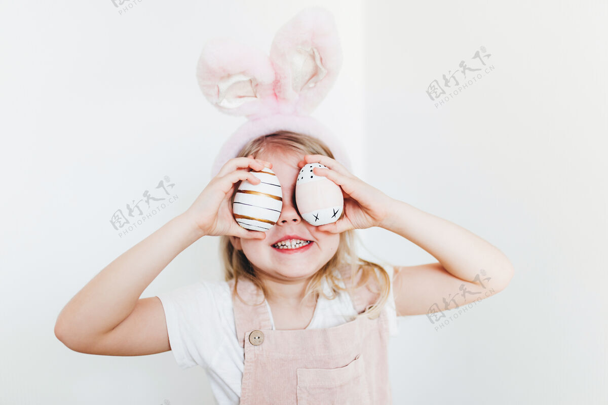 粉色带着复活节彩蛋和兔子耳朵帽子的小女孩女人兔子