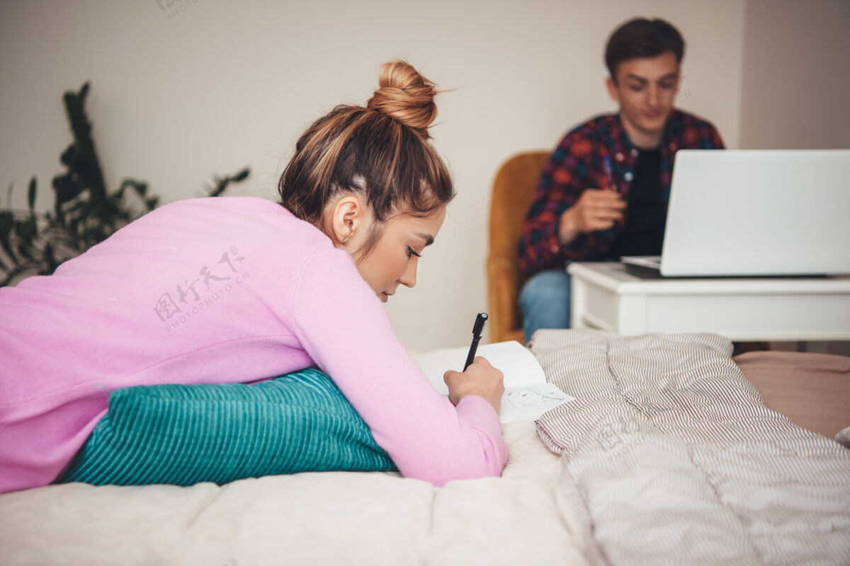 女性年轻的白种人夫妇一边看书 一边躺在床上 一边放松 一边用笔记本电脑数码设备眼镜女人