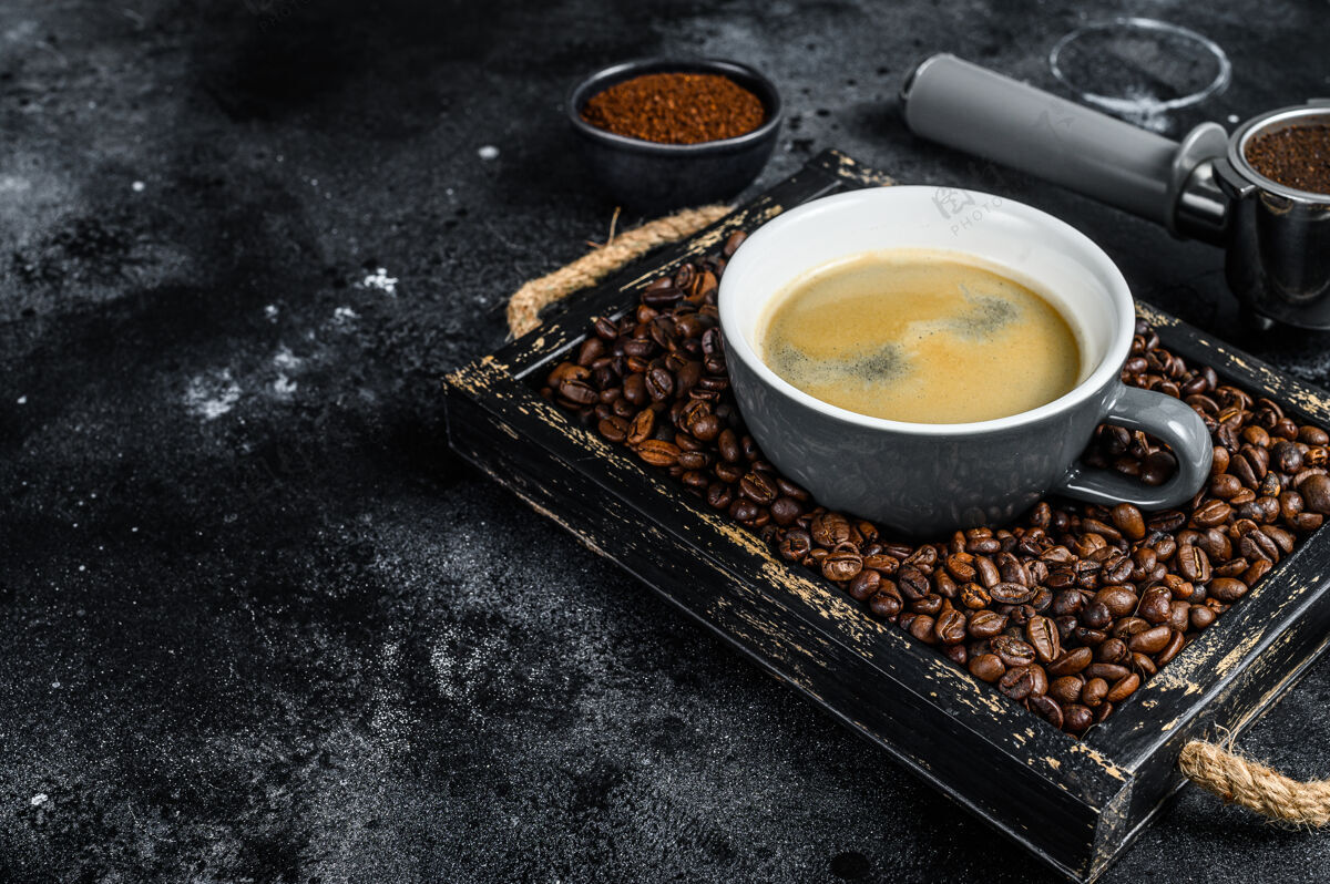 烤的咖啡杯和咖啡豆放在黑色的旧木托盘里桌面查看自助餐厅谷物马克杯