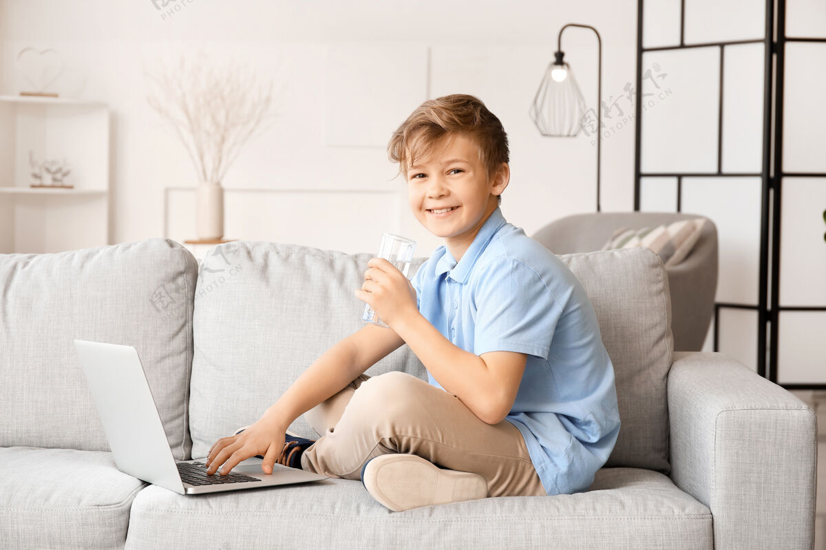 可爱可爱的小男孩拿着笔记本电脑在家喝水矿物过滤饮用