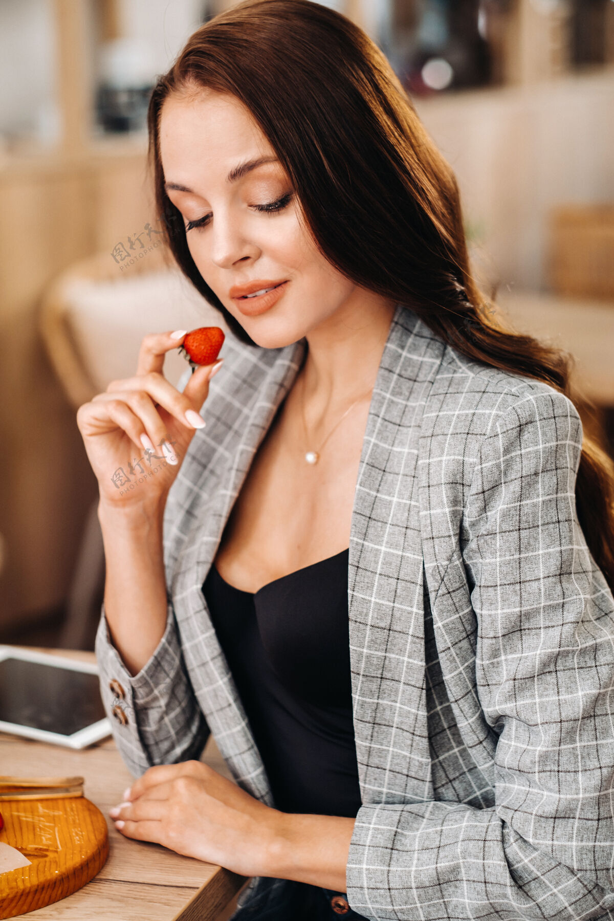 草莓在手一个女人正坐在咖啡馆里吃草莓羊角面包浆果早餐