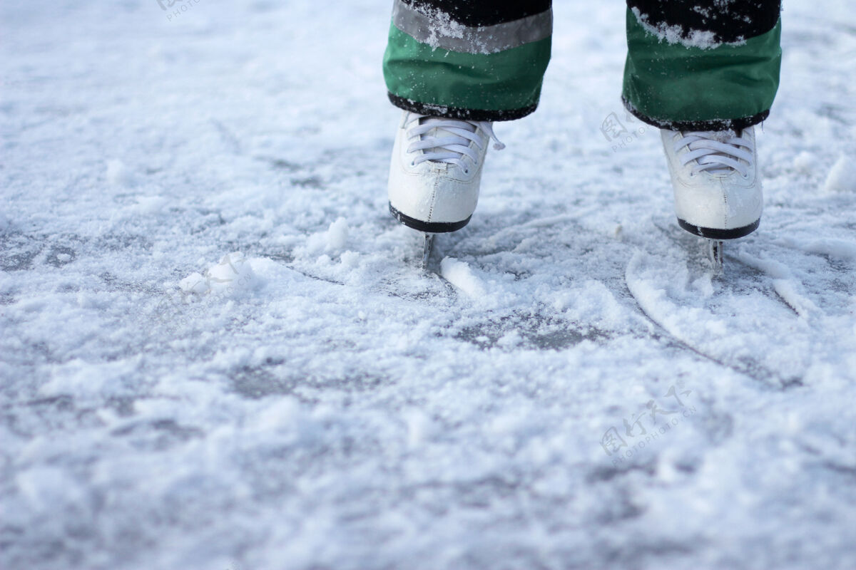 雪穿着白色溜冰鞋的孩子站在地上冰冰在寒冷的冬日滑冰特写训练运动