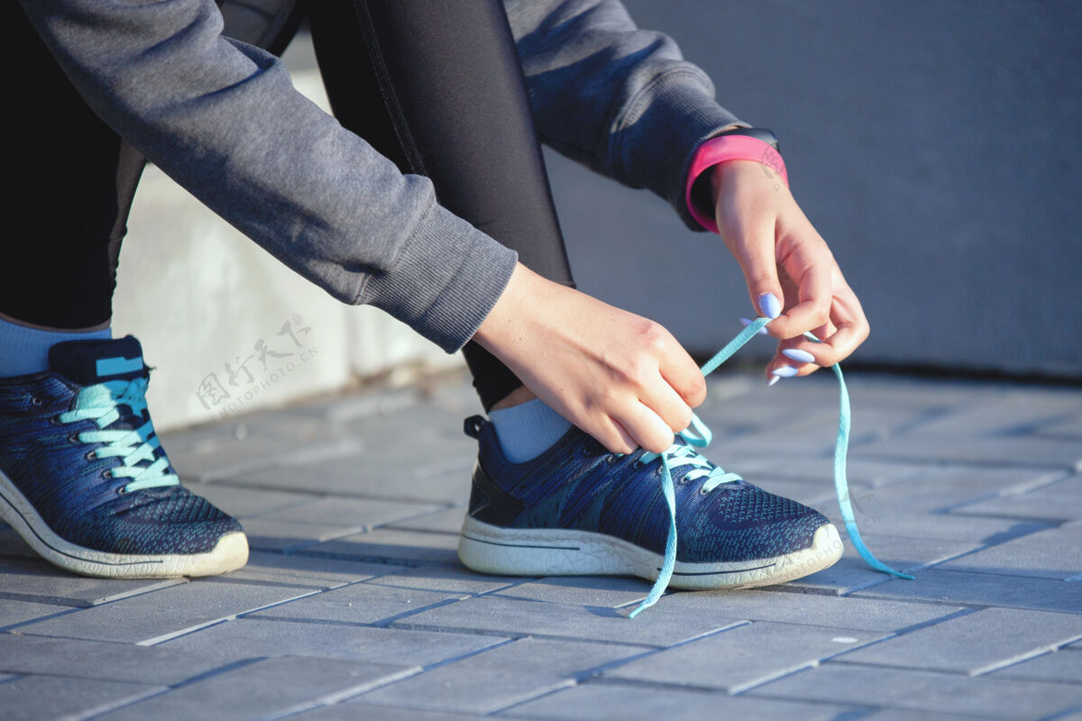 私人教练在城市里热身后 穿着运动服的女性手在楼梯上的运动鞋上系鞋带街头运动员健康