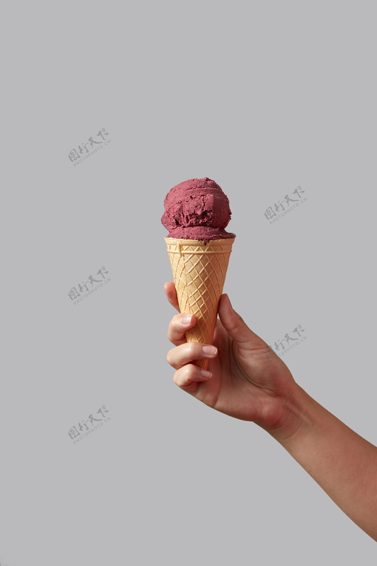 冰淇淋一种浆果红色的冰淇淋 呈圆锥形 呈圆球状 由一个女人的手放在灰色的桌子上墙.夏季复制空间概念甜点香精水果
