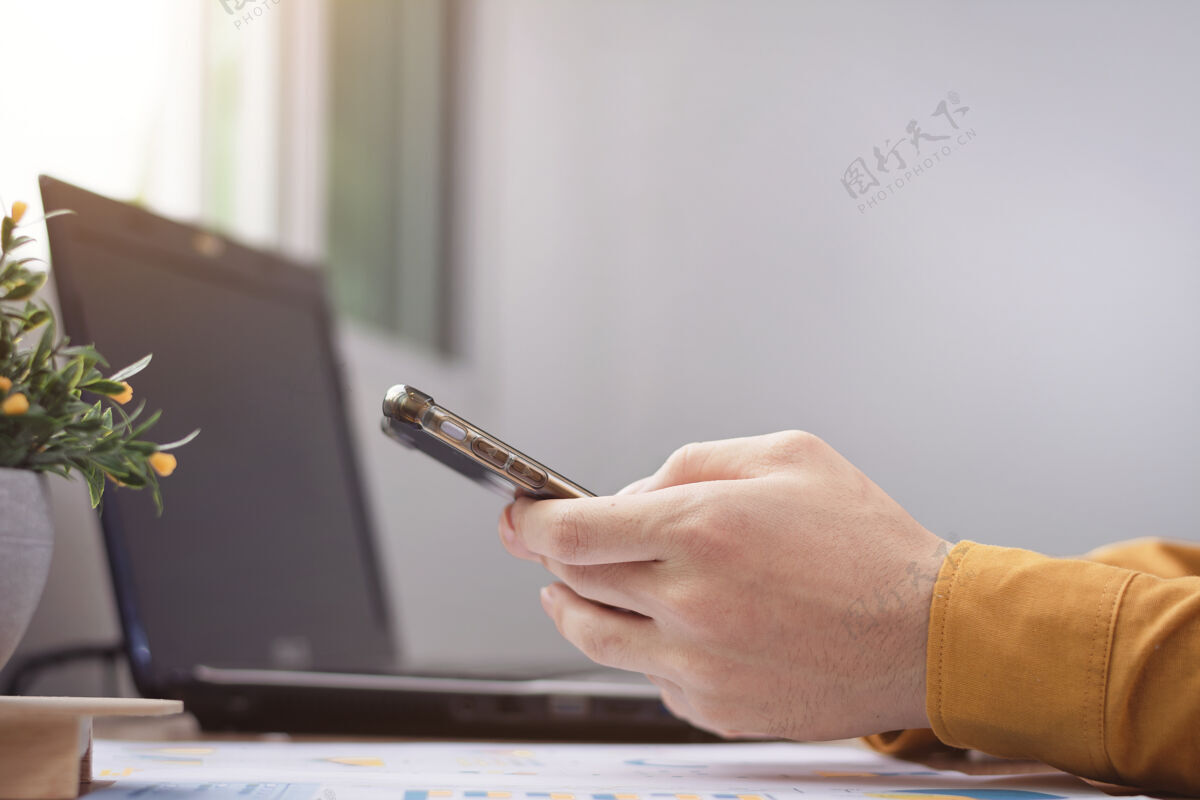 数码商务男士休闲装指着智能手机屏幕在社交网络上聊天设备笔记本电脑手机