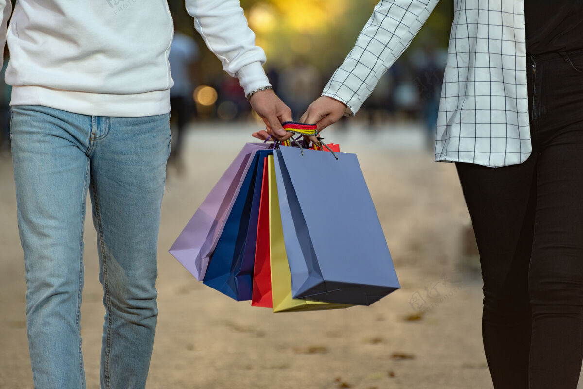 携带恋爱中的情侣拿着五颜六色的纸购物购物袋一起消费者爱情黑色星期五