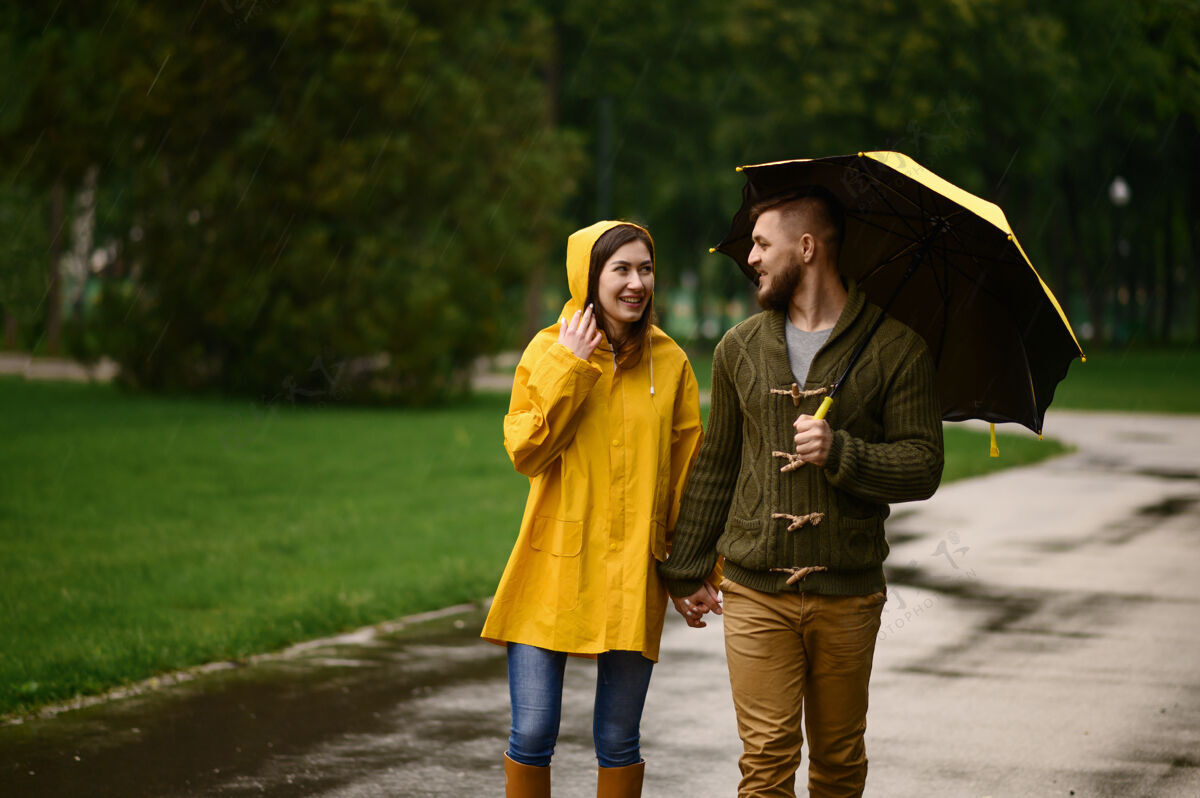 季节带着雨伞的情侣漫步在夏日公园 背景 雨天戴曼女人在雨中的小路上悠闲地走着 小巷里的天气潮湿散步浪漫保护