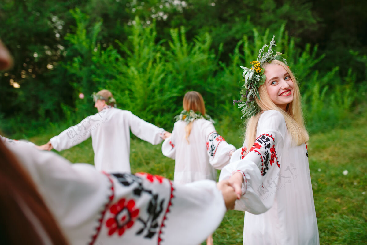 花仲夏年轻穿着斯拉夫人衣服的人在盛夏围着火转服装女性花