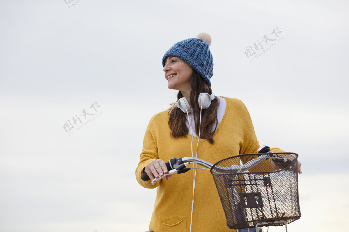 人骑自行车的美女肖像 黄色毛衣 帽子和耳机 文字空间天空美丽人