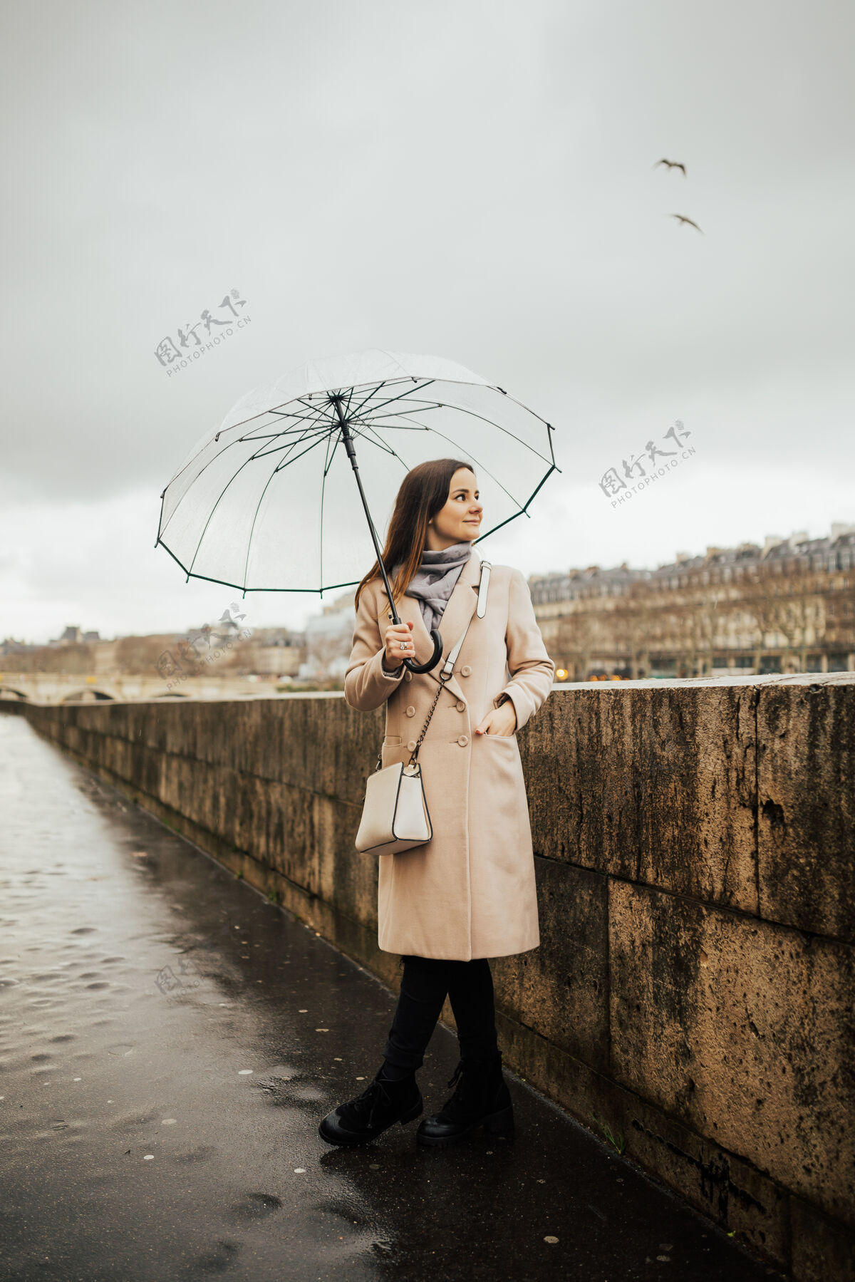 古老时尚的女孩带着透明的雨伞在城市中俯瞰 风景带着模特在雨天地标城市河流