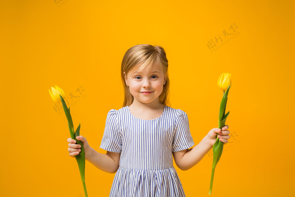 花一个快乐的金发女孩拿着两朵黄色的郁金香单身给予欢呼