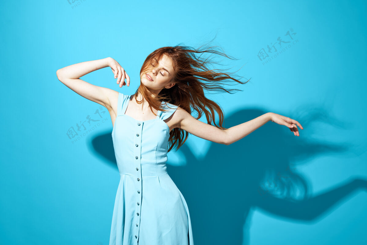 礼服身着蓝色连衣裙的开朗女人摆出迷人的造型欢呼黑发吸引力