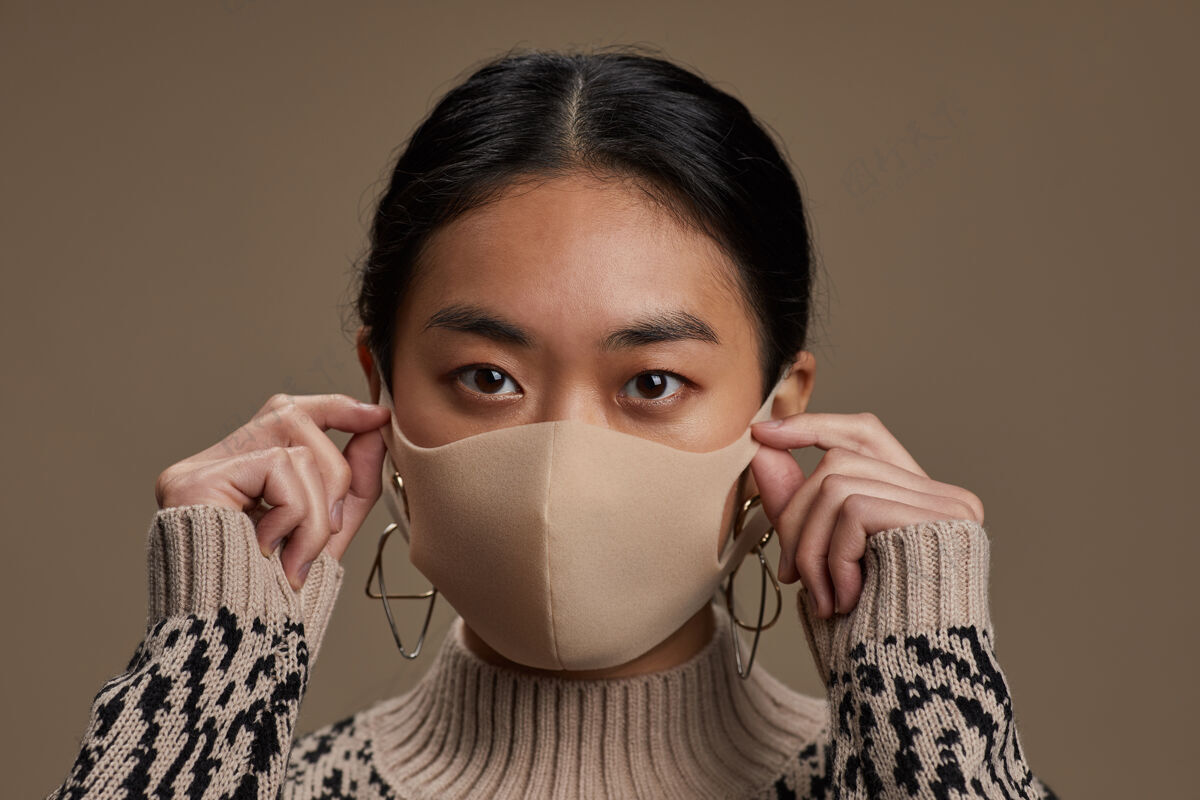 健康与美容戴着防护面具的亚洲女人的特写镜头 看着隔离在灰色墙上的正面流行疾病长相