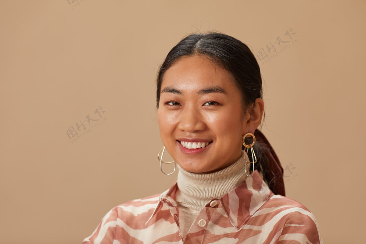 成人亚洲美女微笑的特写镜头被隔离在米色的墙上人脸快乐肖像