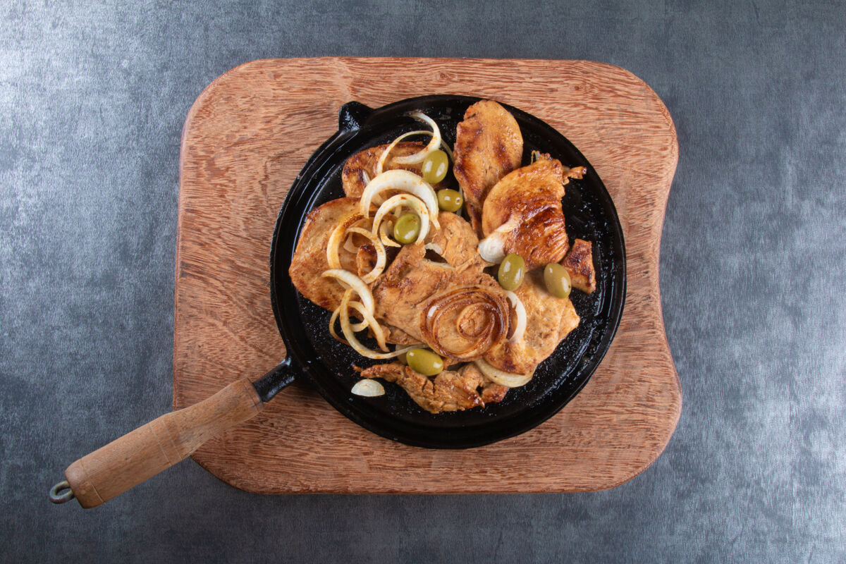 烹饪铁板上的洋葱和橄榄烤鸡俯视图熨斗平底锅餐厅