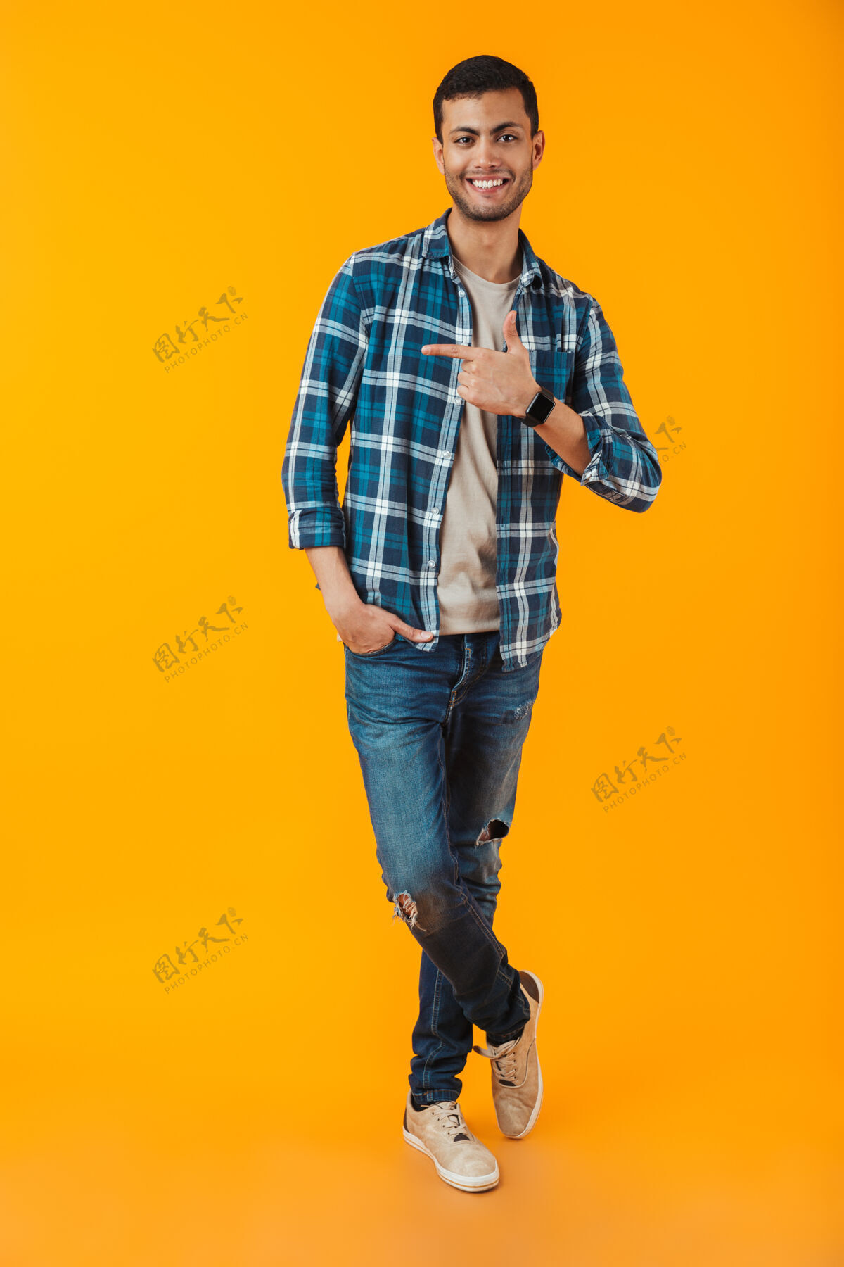 充分一个穿着格子衬衫的快乐的年轻人的全长肖像被隔离在橙色的墙上 手指移开吸引力健身肖像