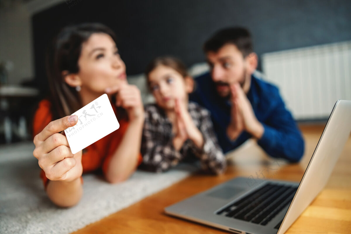 连接父女俩央求妈妈买些东西互联网母亲拿着信用卡在想她是否要花钱金钱选择性用信用卡集中注意力在手上爸爸父亲女儿