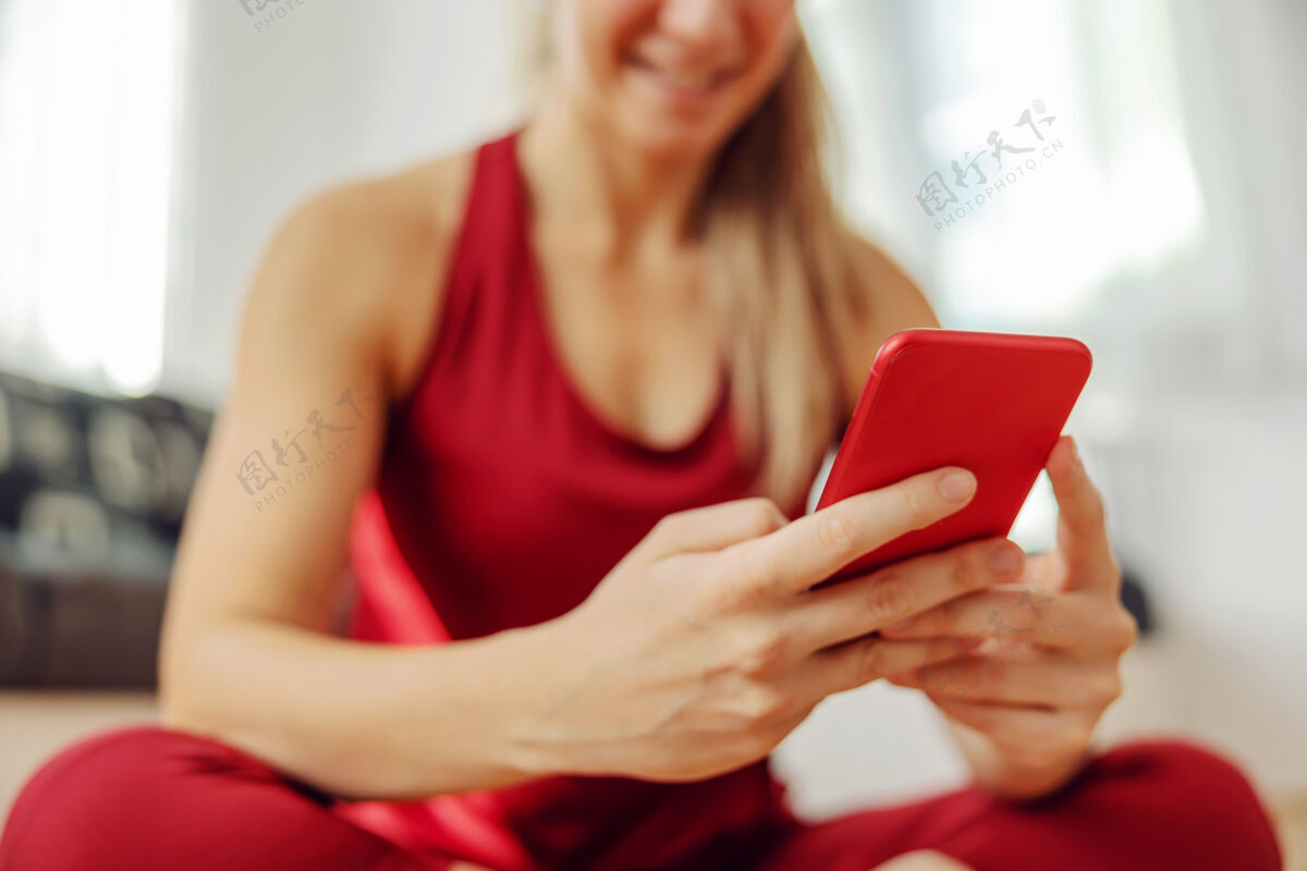锻炼运动员坐在地板上使用智能手机的特写镜头女性运动女人