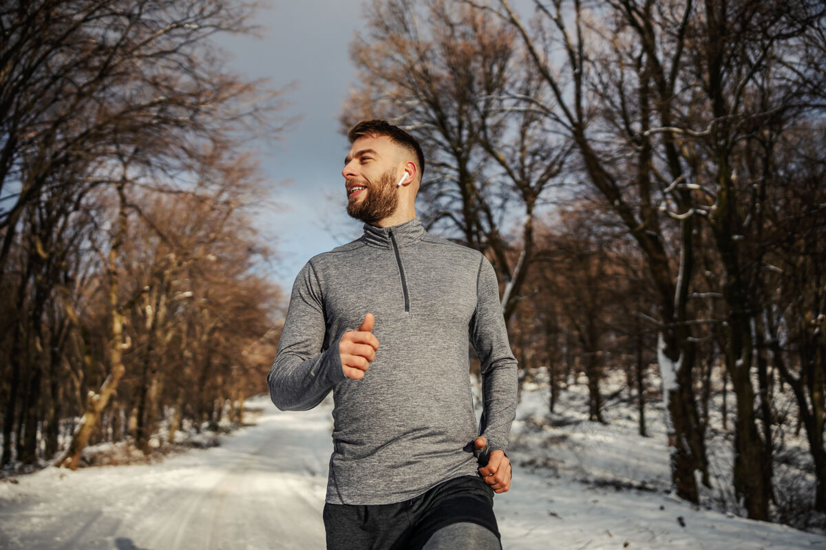 运动员运动员在雪地小道上的森林里慢跑冬天健康生活方式 冬季健身雪天气微笑