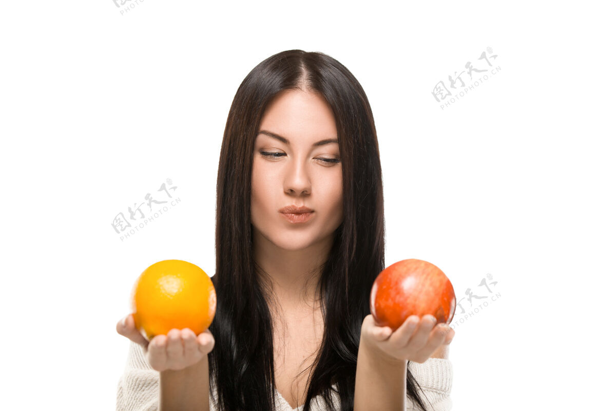 美丽女孩选择苹果和橘子隔离在白色苹果果汁多汁