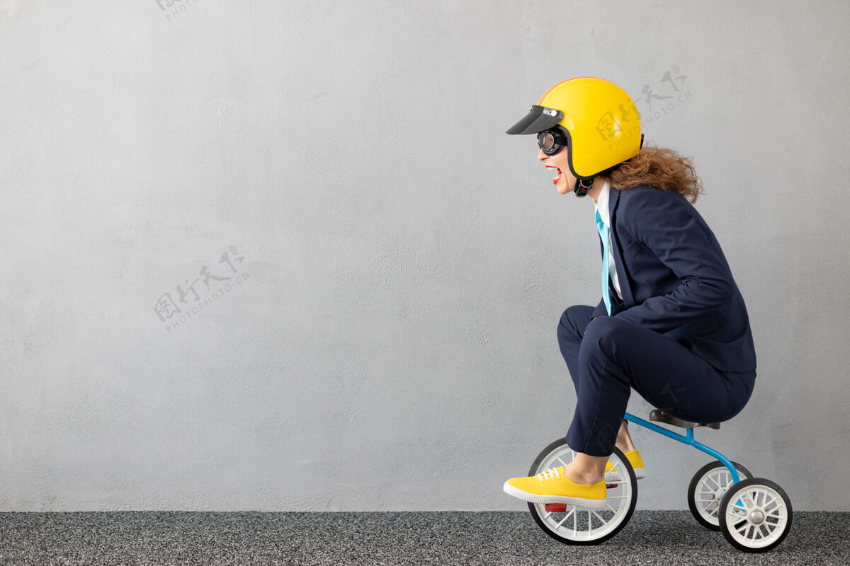 自行车成功的女商人在户外驾驶玩具车赛车梦想动机