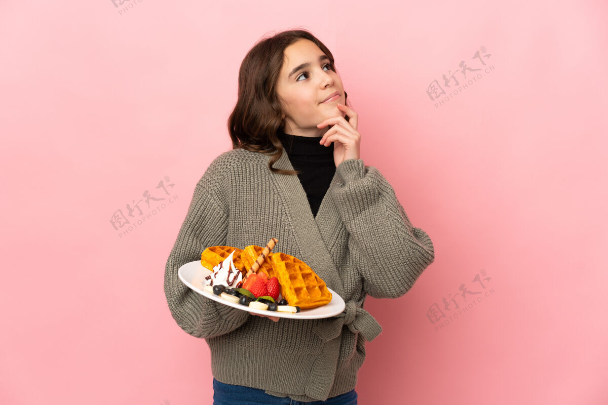 年轻人一个拿着华夫饼的小女孩 站在粉红色的背景上 抬头望去 心中充满疑惑选择奇迹美味