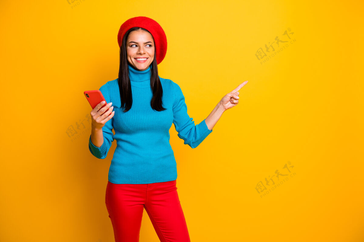 帽子漂亮迷人可爱开朗活泼的女孩肖像使用手机显示复制空间广告商店精品网上购物隔离明亮明亮明亮明亮明亮的黄色墙壁喜欢电话秀